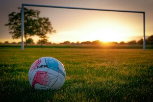 Balón de fútbol sobre el césped al atardecer