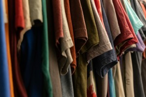 Camisetas de colores colgadas en perchas dentro de un armario