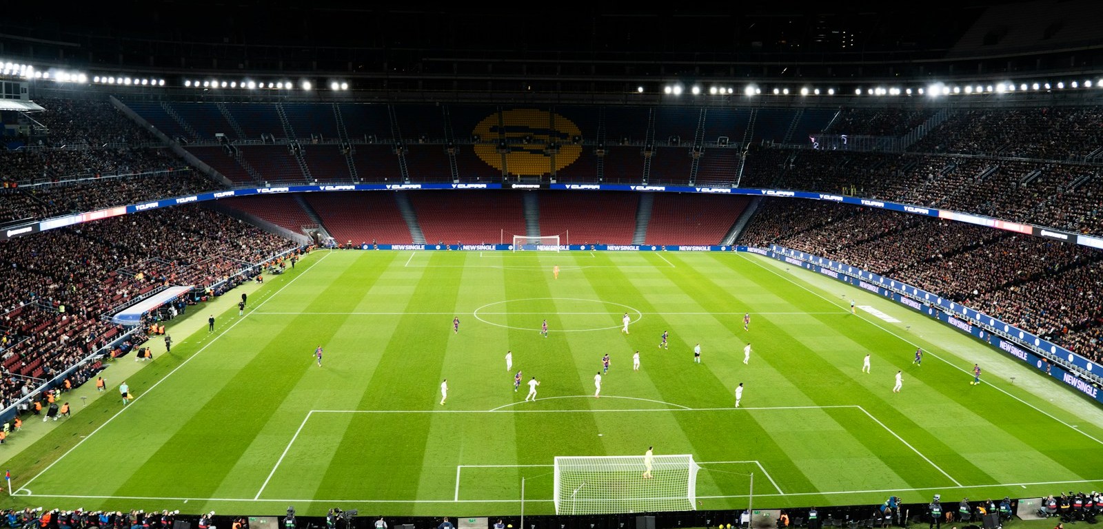 Partido de fútbol en un estadio lleno e iluminado por la noche