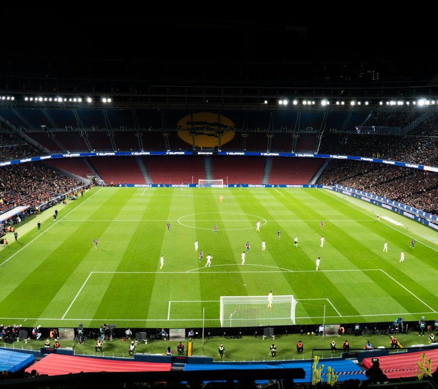 Partido de fútbol en un estadio lleno e iluminado por la noche