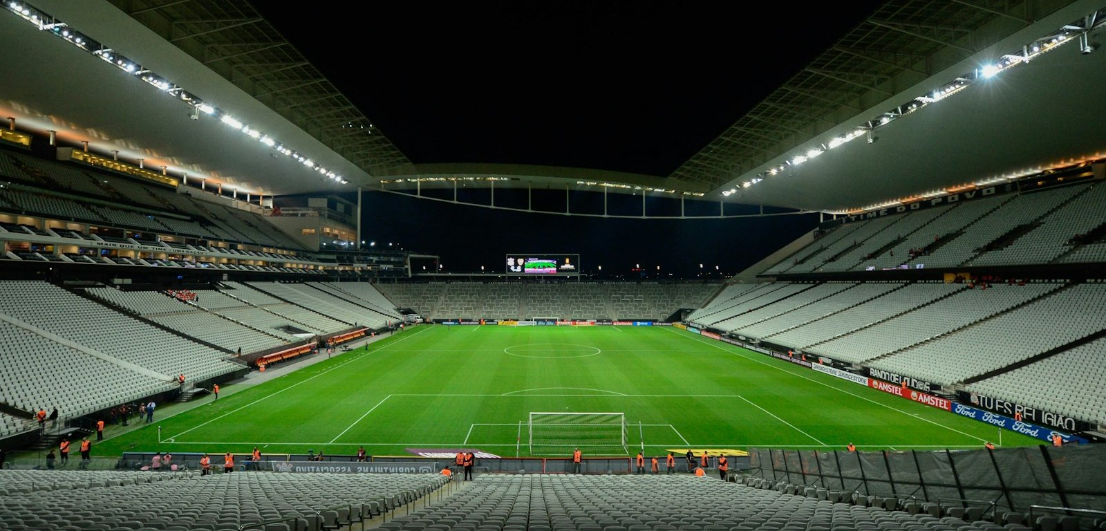 Estadio de fútbol vacío con la cancha iluminada de noche