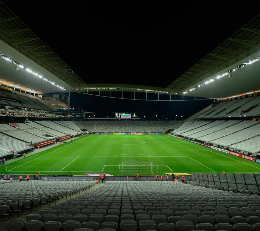 Estadio de fútbol vacío con la cancha iluminada de noche