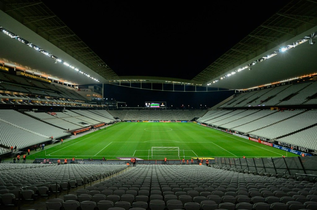 Estadio de fútbol vacío con la cancha iluminada de noche