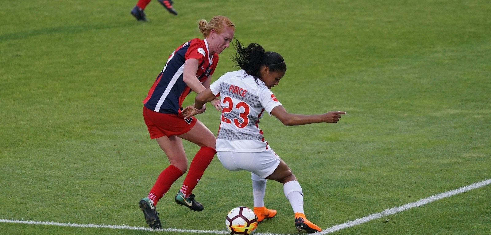 Dos jugadoras disputan la pelota en una cancha de fútbol