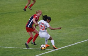 Dos jugadoras de fútbol disputan el balón en una cancha de césped