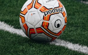 Un balón de fútbol sobre el césped junto a una línea blanca de la cancha