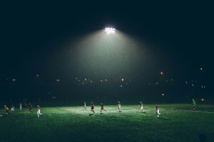 Partido de fútbol nocturno en una cancha de césped iluminada por reflectores