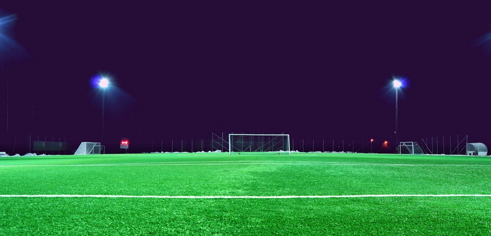Cancha de fútbol vacía bajo las luces del estadio por la noche