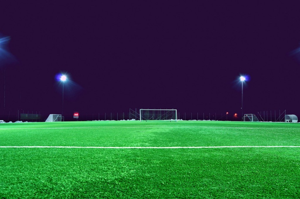 Cancha de fútbol vacía bajo las luces del estadio por la noche