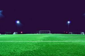Cancha de fútbol vacía iluminada por los focos del estadio de noche