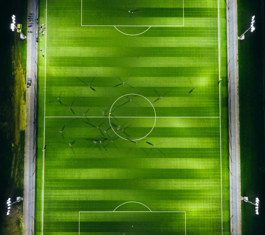 Vista aérea de una cancha de fútbol iluminada por reflectores de noche