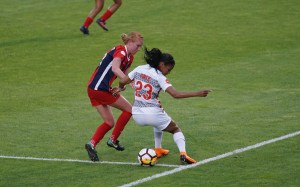Dos jugadoras de fútbol disputan el balón en una cancha de césped