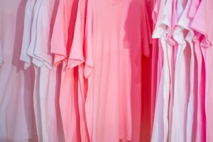 Camisetas lisas en tonos rosa y blanco colgadas en perchas