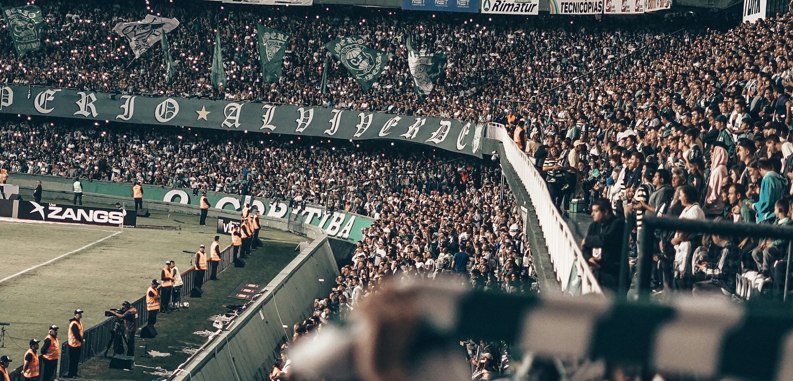 Tribunas llenas de público en un estadio de fútbol iluminado de noche