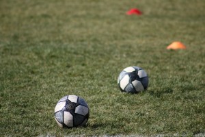 Dos balones de fútbol sobre el césped de una cancha de entrenamiento