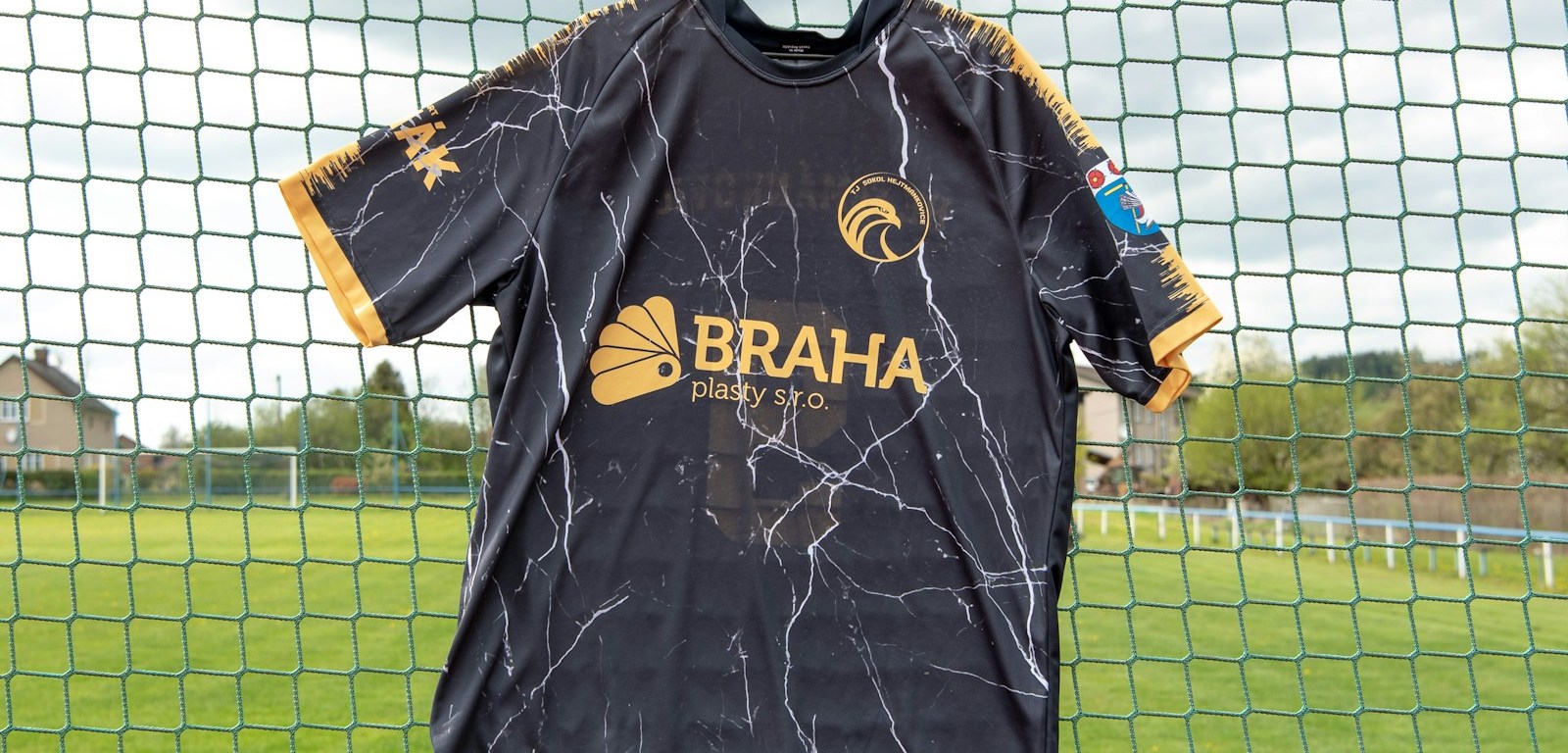 Camiseta de fútbol negra y dorada colgada sobre una cerca