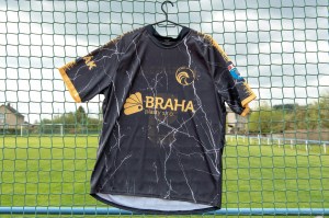 Camiseta de fútbol negra y dorada colgada sobre una cerca