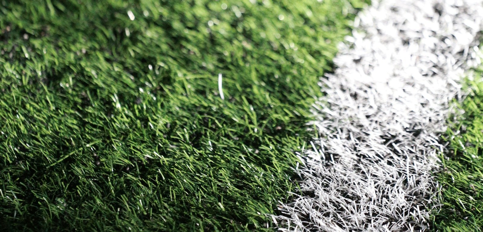 Pelota de fútbol sobre el césped con luces de estadio desenfocadas al fondo