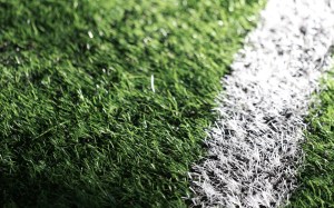 Pelota de fútbol sobre el césped con luces de estadio desenfocadas al fondo