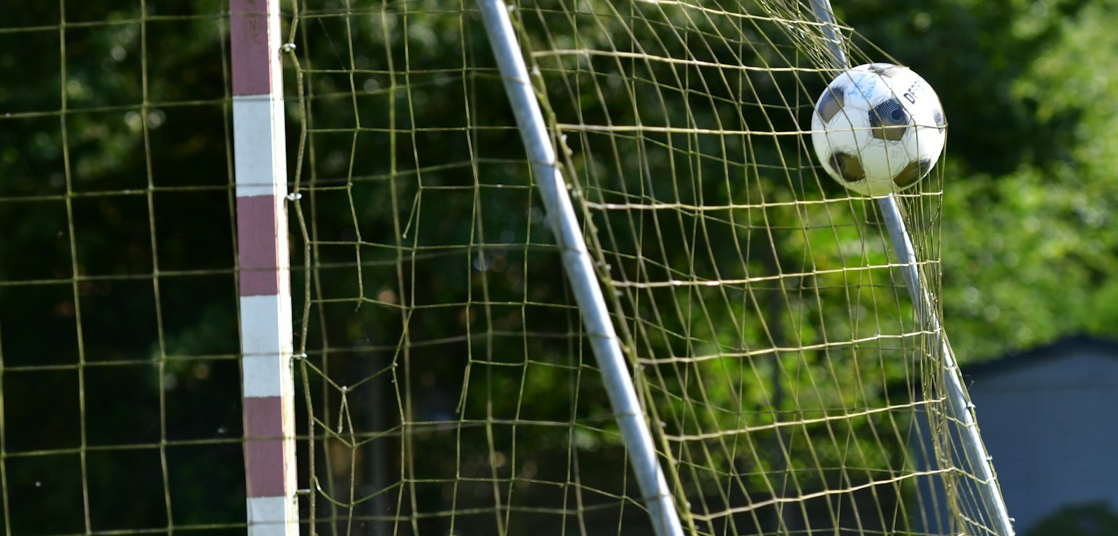 Pelota de fútbol en el aire a punto de entrar en la red de un arco