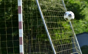 Pelota de fútbol en el aire a punto de entrar en la red de un arco